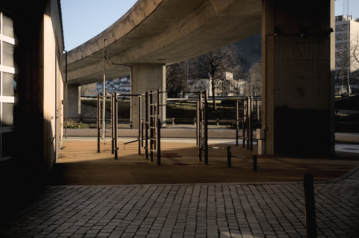 Outdoor gym under a motorway bridge with various horizontal bars and monkey bars.